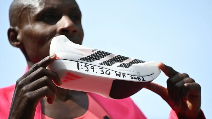 Sabastian Sawe montre sa chaussure, qui a en partie permis son record du monde, sur le marathon de Londres le 26 avril 2026. (JUSTIN TALLIS / AFP)