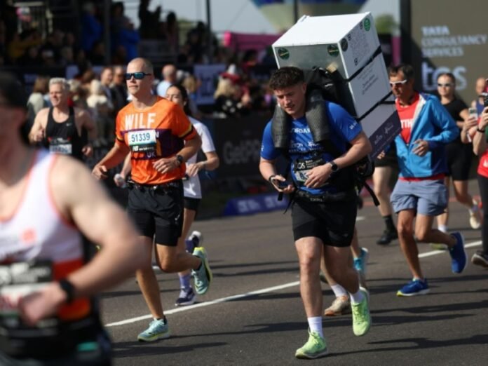 Le coureur Jordan Adams porte un frigo sur son dos au départ du marathon de Blackheath