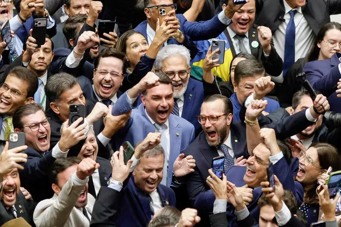 Le sénateur Flavio Bolsonaro (fils aîné de l’ancien président Jair Bolsonaro, au centre) célèbre le vote qui annule le veto du président Lula sur un projet de loi visant à réduire les peines des personnes condamnées pour tentative de coup d’Etat, au Parlement de Brasilia, le 30 avril 2026. 