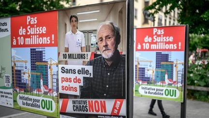Des affiches de campagne pour et contre un référendum national sur une initiative anti-immigration, à Genève (Suisse), le 4 juin 2026. (FABRICE COFFRINI / AFP)