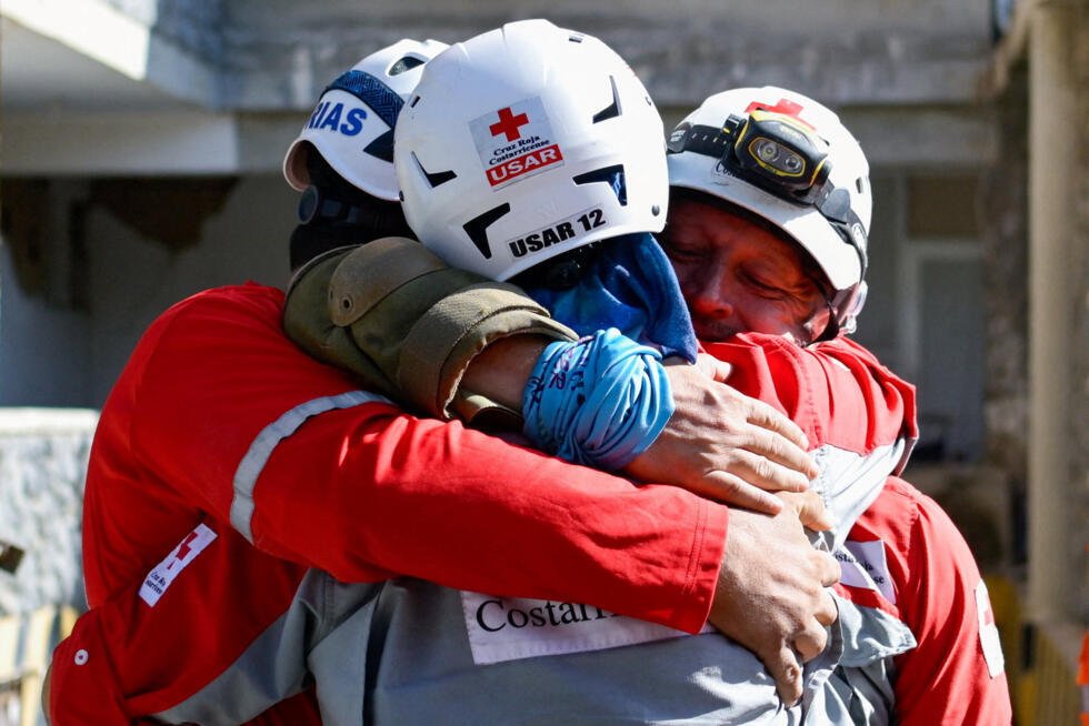Des sauveteurs s'étreignent après avoir extrait Hernán Alberto Gil, un survivant qui était resté piégé pendant plus d'une semaine après les séismes du 24 juin, sous un centre commercial effondré à La Guaira, au Venezuela, le 2 juillet 2026.