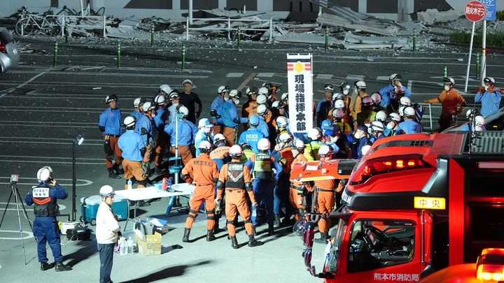 Des pompiers se préparent à des opérations de secours sur le parking du centre commercial Aeon Mall Kumamoto, à Kashima (Japon), le 28 juillet 2026. (KAZUKI WAKASUGI / YOMIURI / AFP)