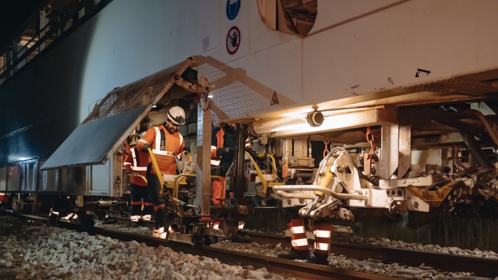 Sur le chantier de renouvellement des voies sur la ligne Paris-Cherbourg, les agents travaillent sous le train usine Sur le chantier de renouvellement des voies sur la ligne Paris-Cherbourg, les agents travaillent sous le train usine