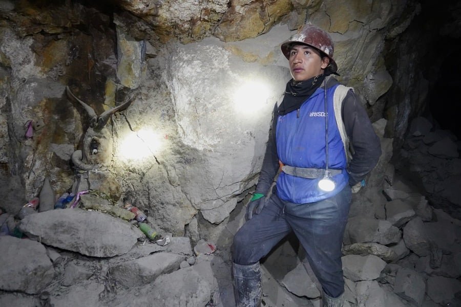 Ariel, un ancien mineur reconverti en guide, se tient aux côtés d'une effigie d'El Tío, créature emblématique du folklore minier bolivien. | Izia Rouviller
